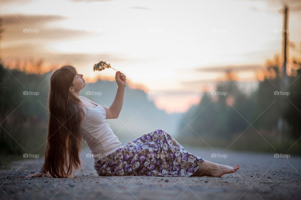 Beautiful young woman on road at sunset 