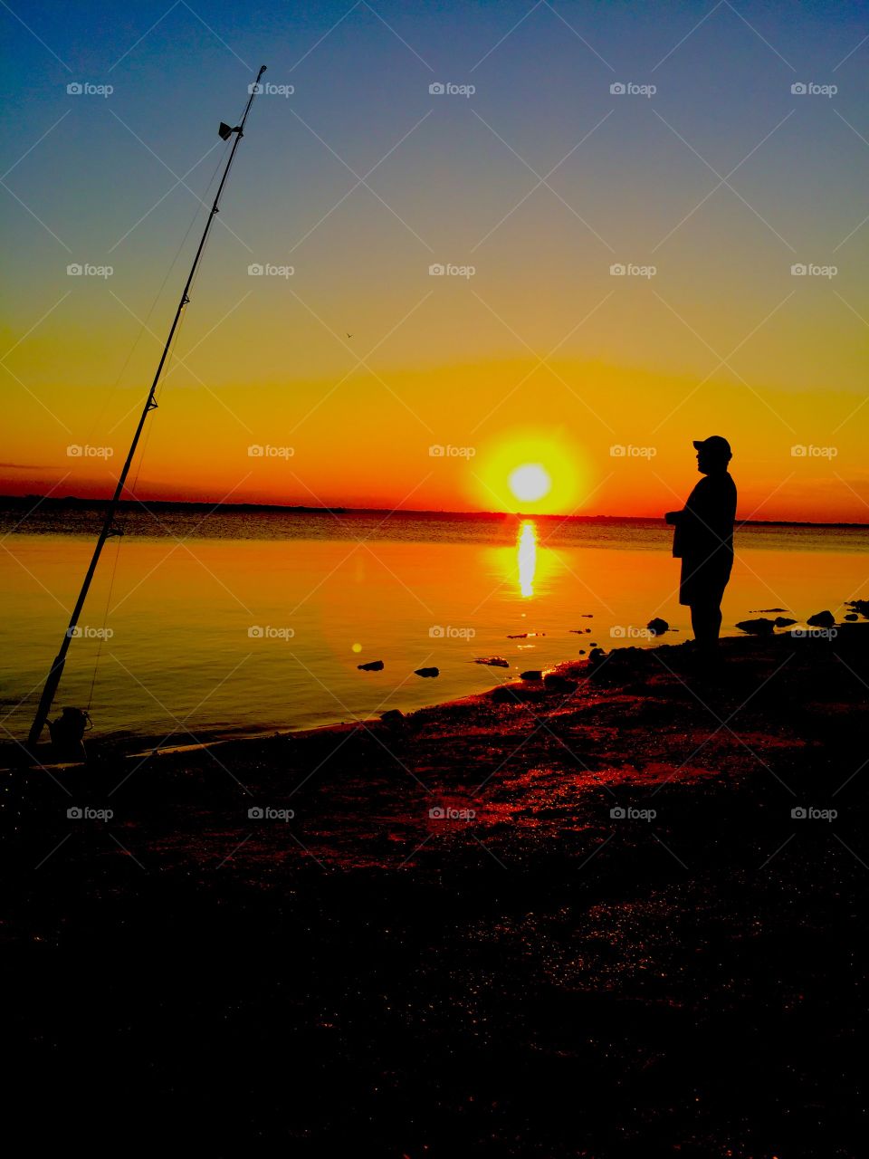 Silhouette of a fisherman in the sea at sunset