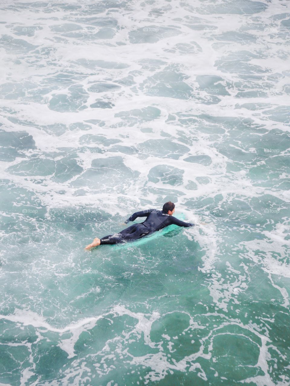 Surfer pedaling to catch a wave.