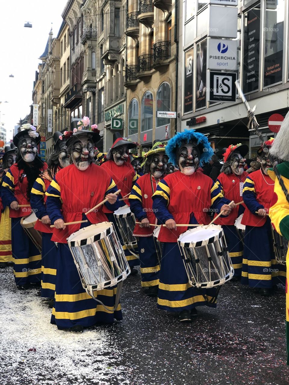 a large crowd of people running in the city among large buildings. a crowd of people in masquerade costumes and masks at a fundamental festival in Switzerland. people in bright costumes on a holiday