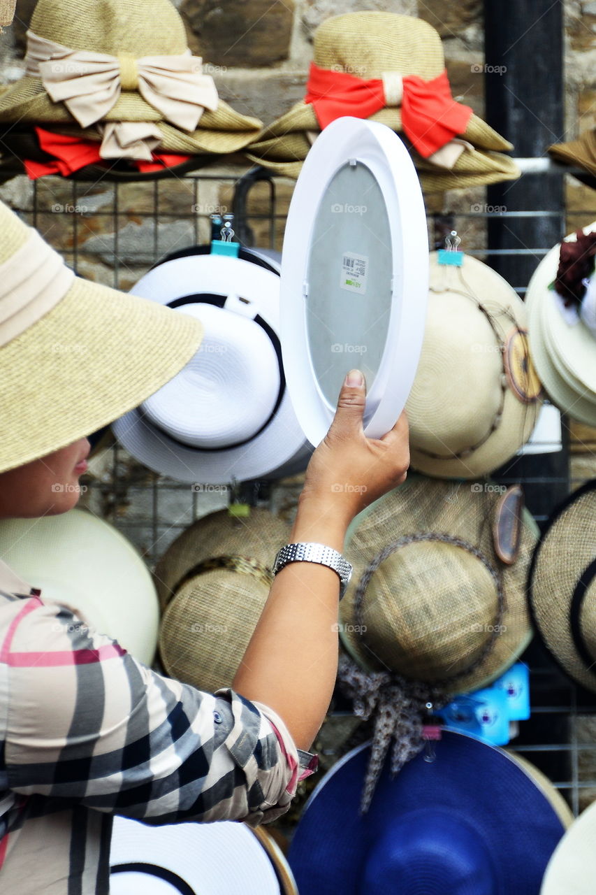 a woman wearing a hat and looks in a mirror