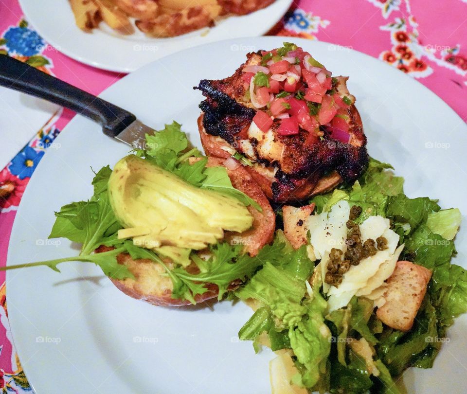 Charred fish sandwich with tomato, avocado, lettuce, capers, herbs 