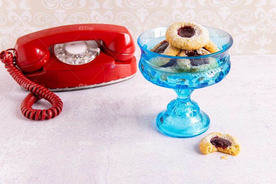 Retro image of thumbprint cookies in a vintage coupe dish next to a vintage rotary telephone 