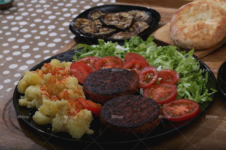 Hamburger vegani beyond meat alla piastra con insalata di patate lattuga e pomodori