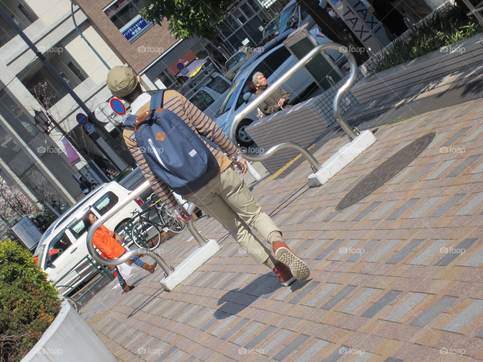 Young Japanese Man Walking Down the Street with Backpack and Striped Shirt