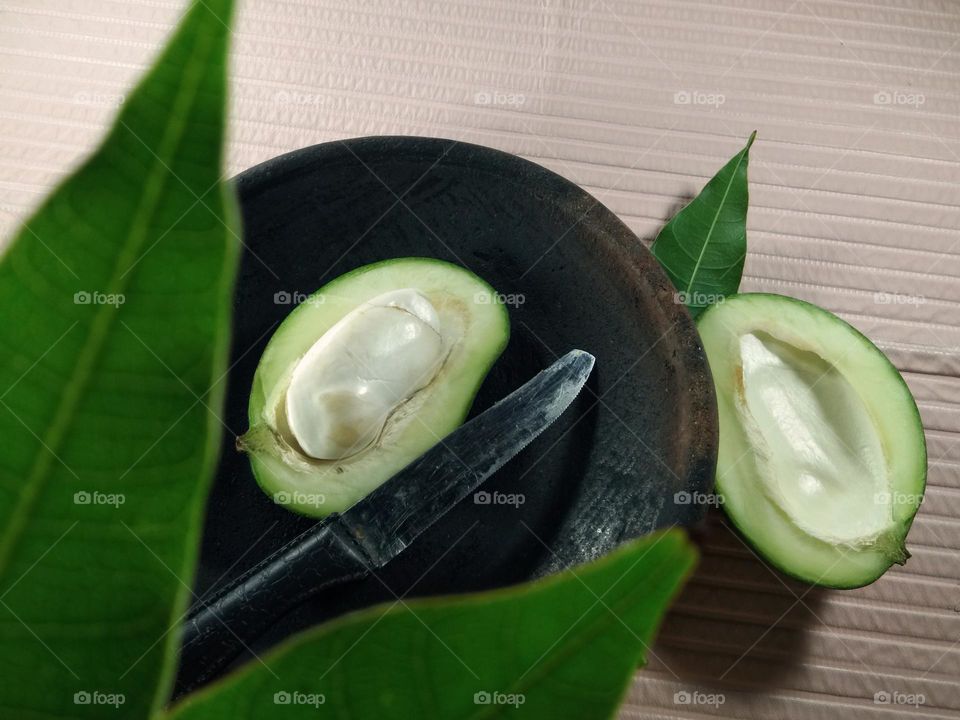 top view of cut of green mango on clay plate