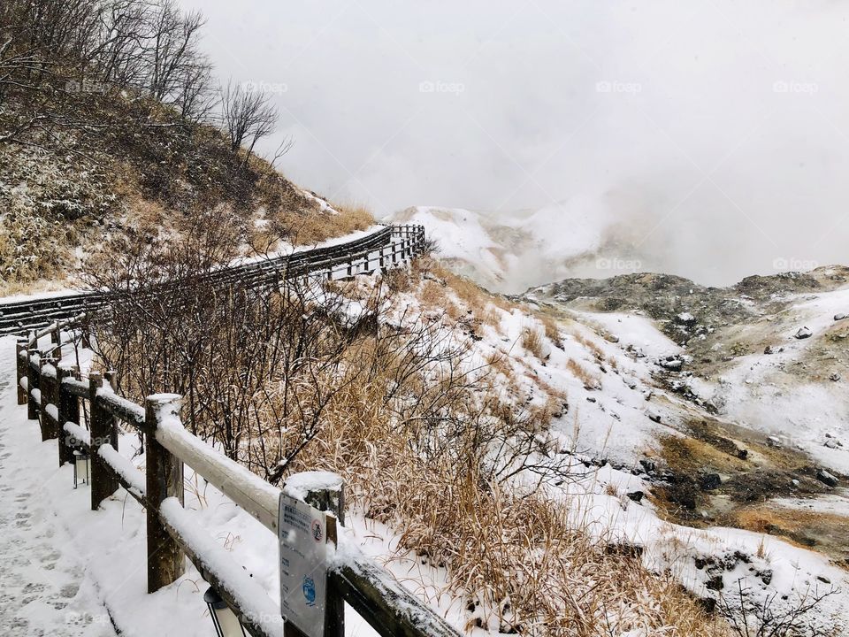 Jigokudani or Hell Valley wooden walkway bridge in the town of Noboribetsu Onsen, hot steam vents, sulfurous streams and other volcanic activity, hot spring waters, Hokkaido, Japan, winter with snow