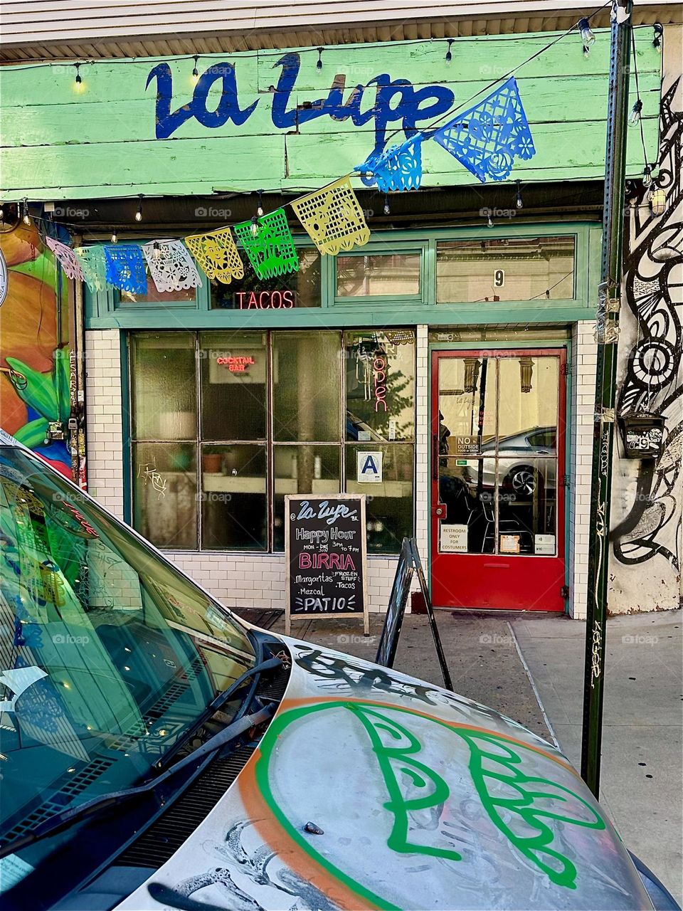 This is the popular club and restaurant “La Lupe” on “Jefferson St” off “Broadway” in “Bushwick”, Brooklyn. A spectacular larger than life art mural leads up to it that extends over almost an entire city block. 2024. Hypnotic Productions