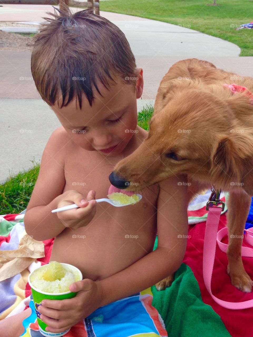 A little boy generously shares his shaved ice with his rescue pup, Audrey Pearl, during a hot summer afternoon.