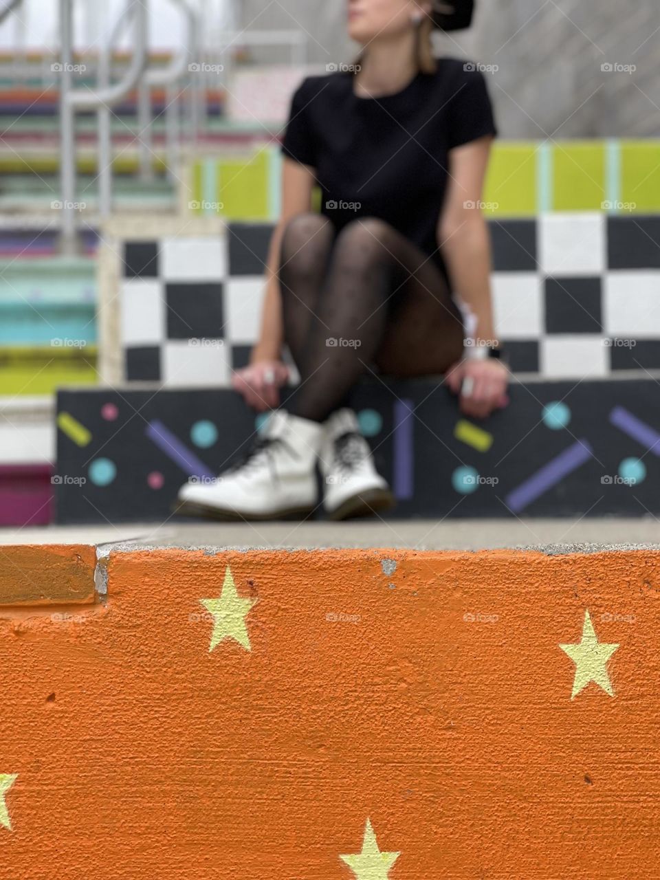 Woman sitting on colorfully painted stairs outdoors in an urban setting 