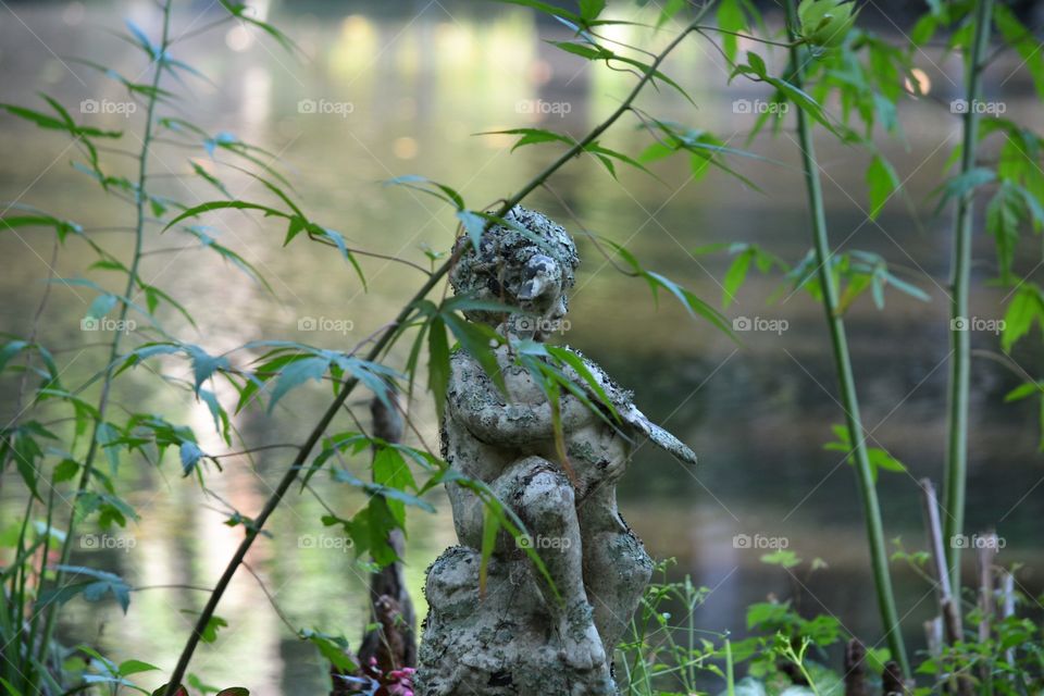 Child Statue Hidden behind Vines in a Garden