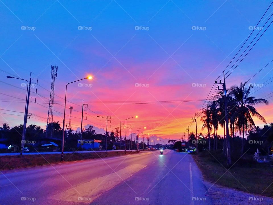 The setting sun casts a red glow on the road.