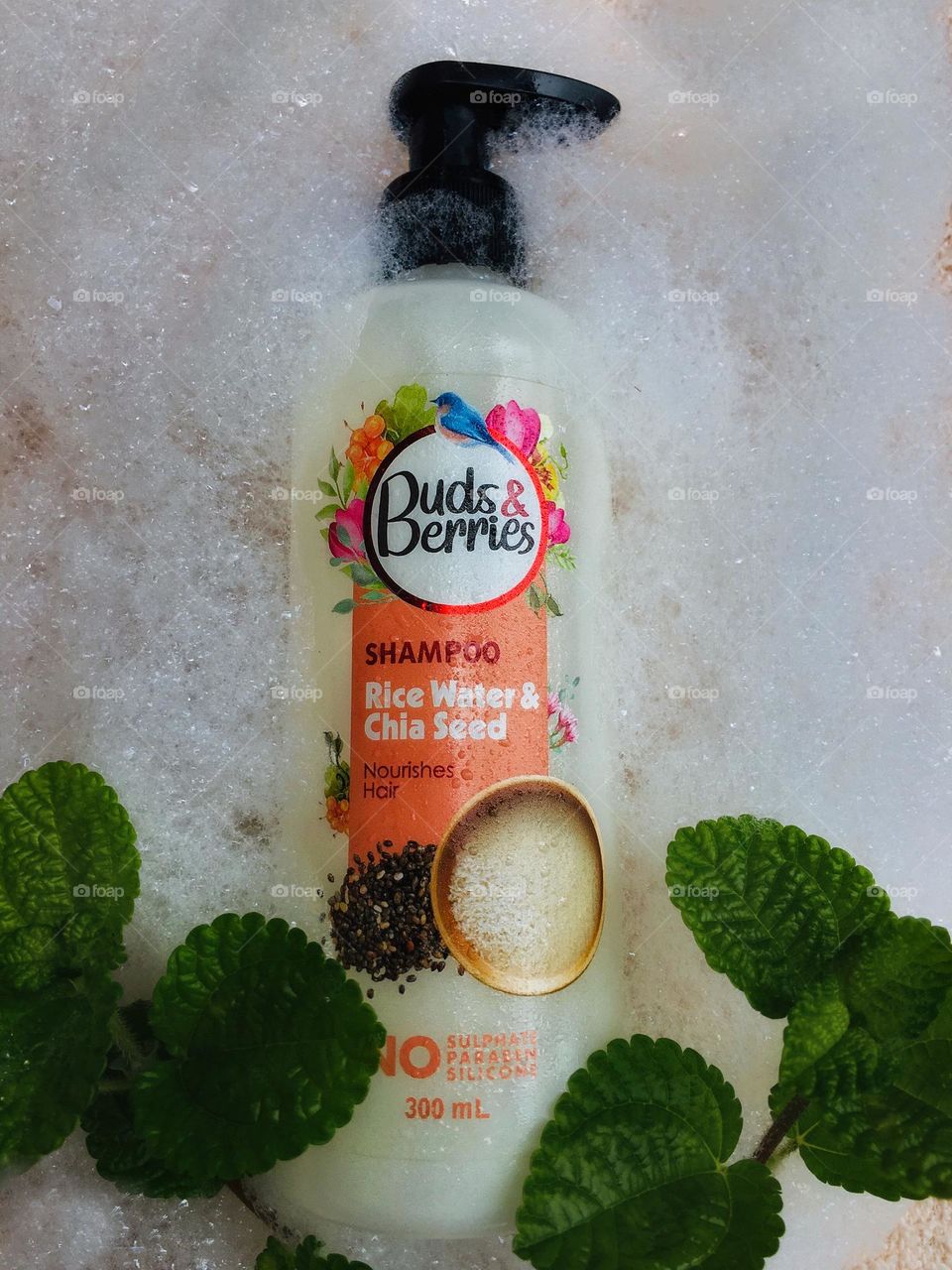 A Buds & Berries shampoo with the rise water and chia seed flavour placed within the white foam. An effective and healthy shampoo with no sulphate in it. 