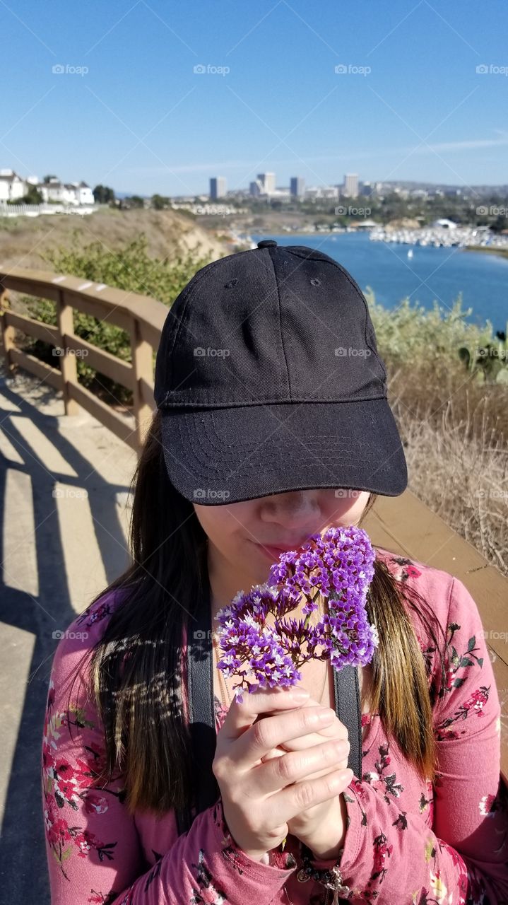 fashionable woman holding and smelling a sea lavender flower background of the beautiful view of the bay and the city