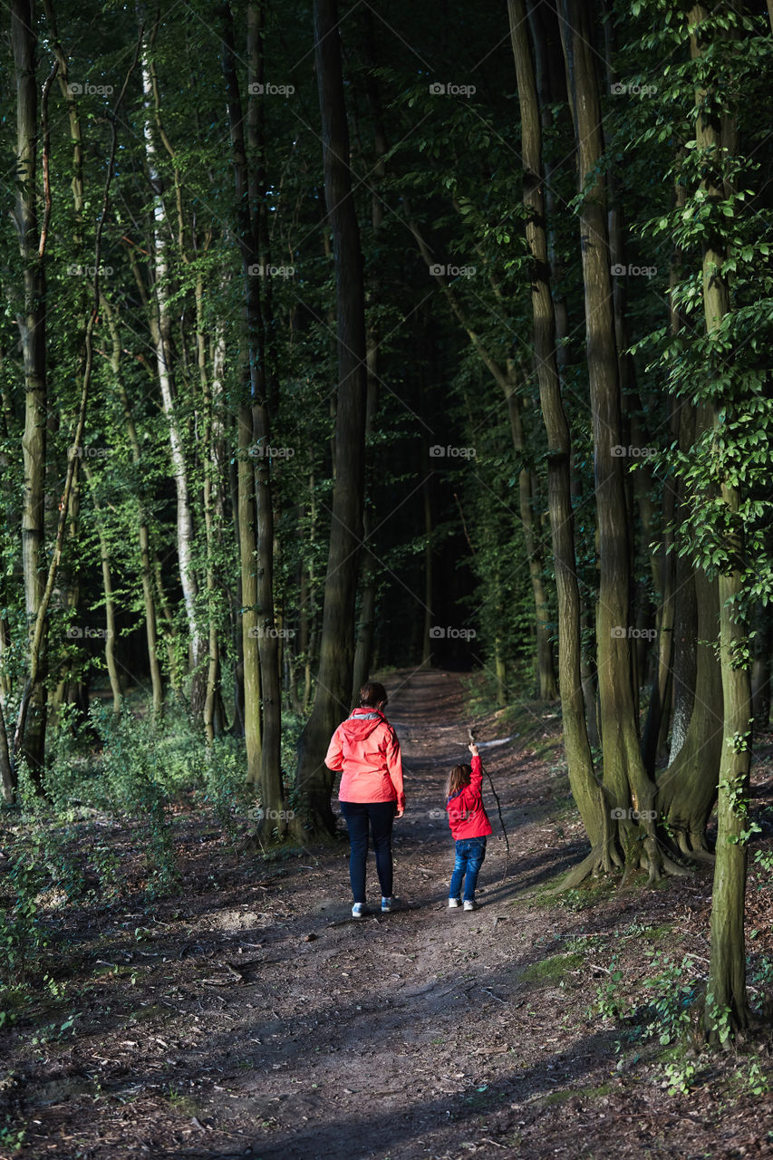 Mother with her little daughter walking through the forest. Spending leisure time, vacation on wandering in forests, close to nature