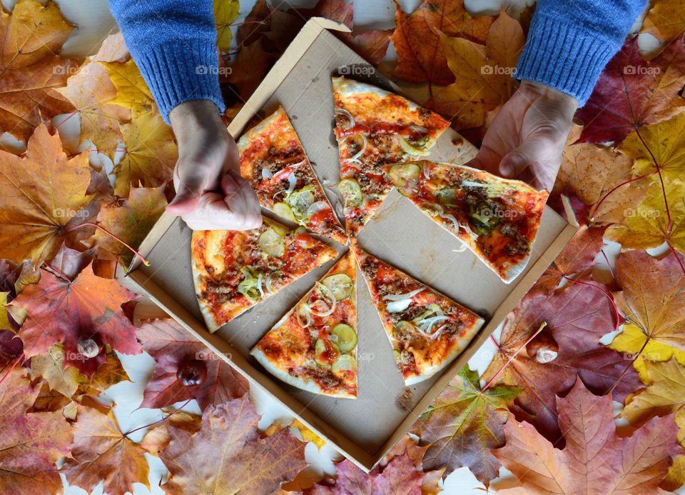 High angle view of person's hand holding pizza box