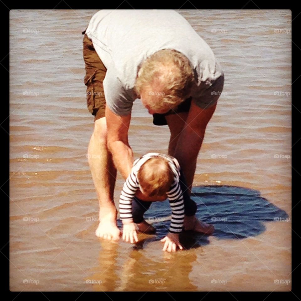 Grandad and grandchild paddling in the sea