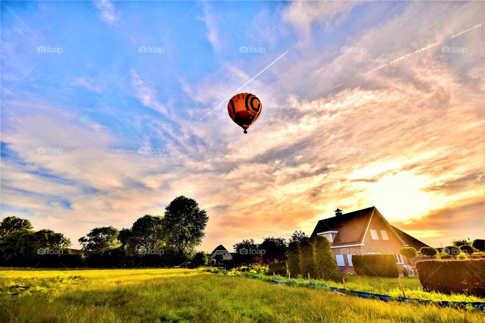 Rural landscape with hot air balloon and clouds in the sky at dawn