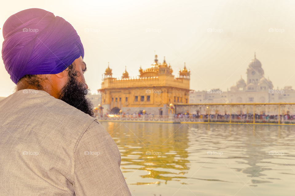 Unidentifiable Punjabi Sikh pilgrim devotee "Nihang Warrior" sitting by the holy pool and meditating in front of Golden Temple ("Harmandir Sahib Darbar Gurudwara") Amritsar, Punjab, India, Asia.