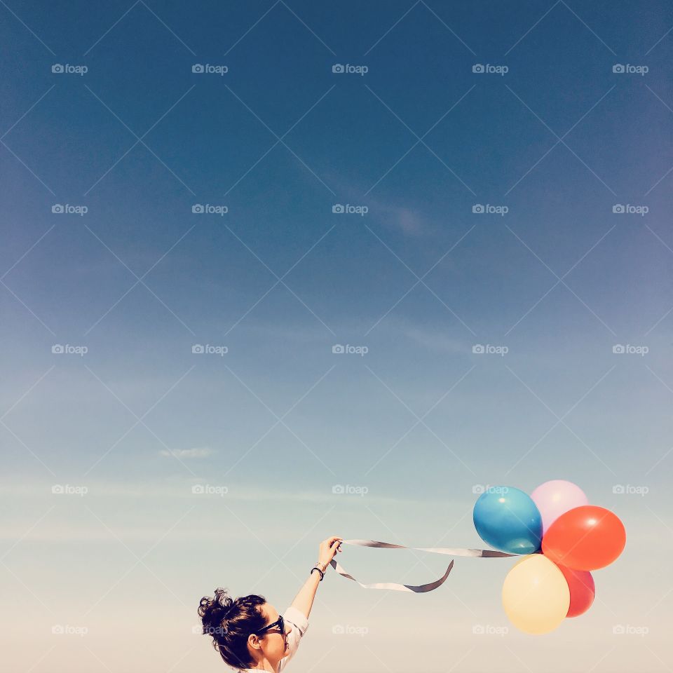 Woman holding balloon against sky