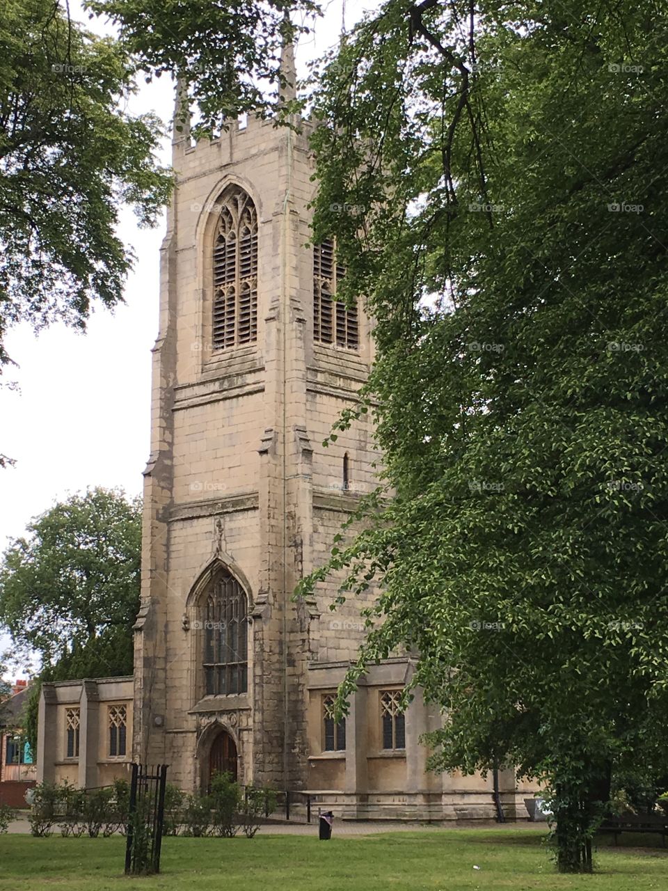 All Saints Church in Gainsborough, England with 15th Century tower, surrounded by trees