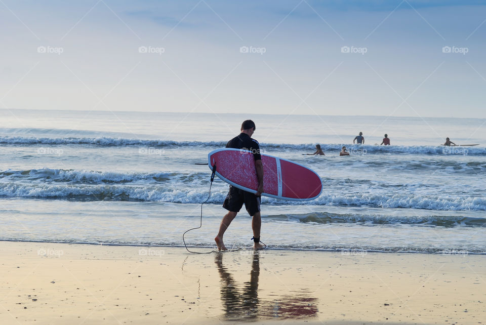 Man with Surfboard Joining His Friends in the Water