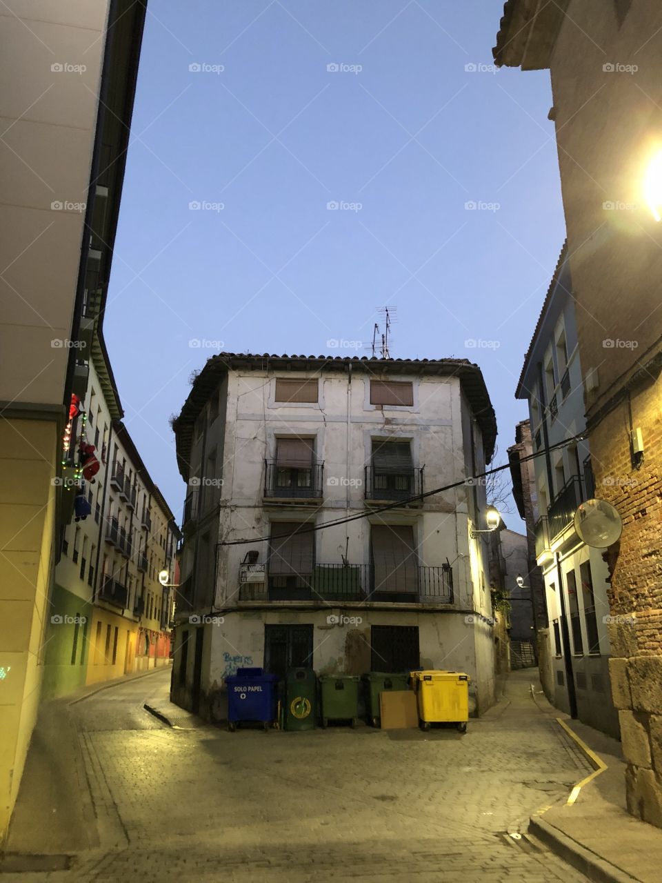Crossroads in an old town with well-lit clean although weather-beaten streets. It’s dusk and the crowd has gone away leaving nothing but the wind 