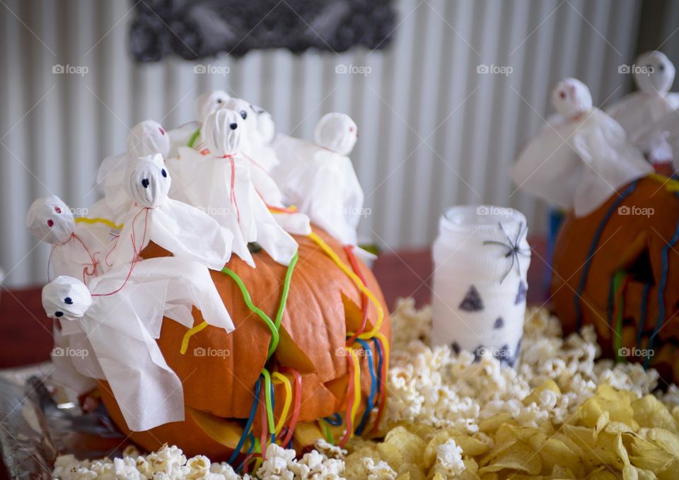 Decoration for Halloween.  The large pumpkin is decorated with napkin ghosts, worm candy chips and popcorn.