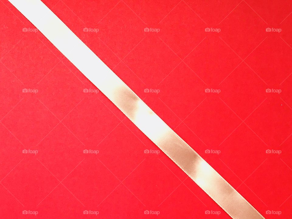 A white shiny ribbon on a bright red background 