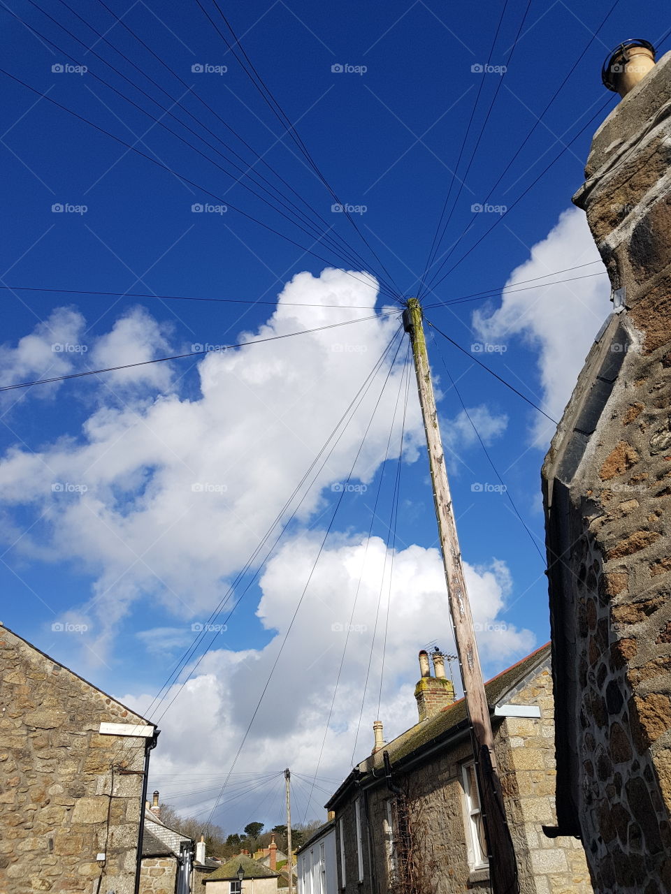 The thin wires cut through the clouds and blue sky to connect a small seaside village
