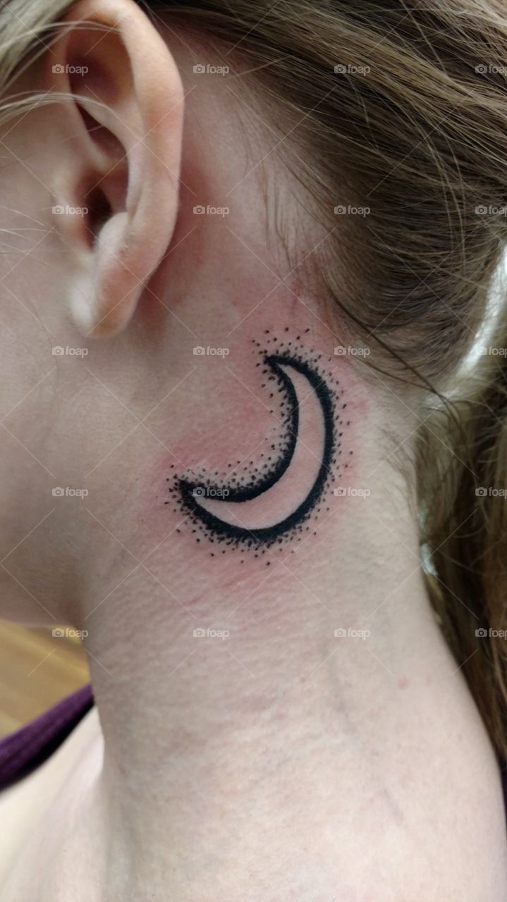 A fresh tattoo on a females neck of a moon