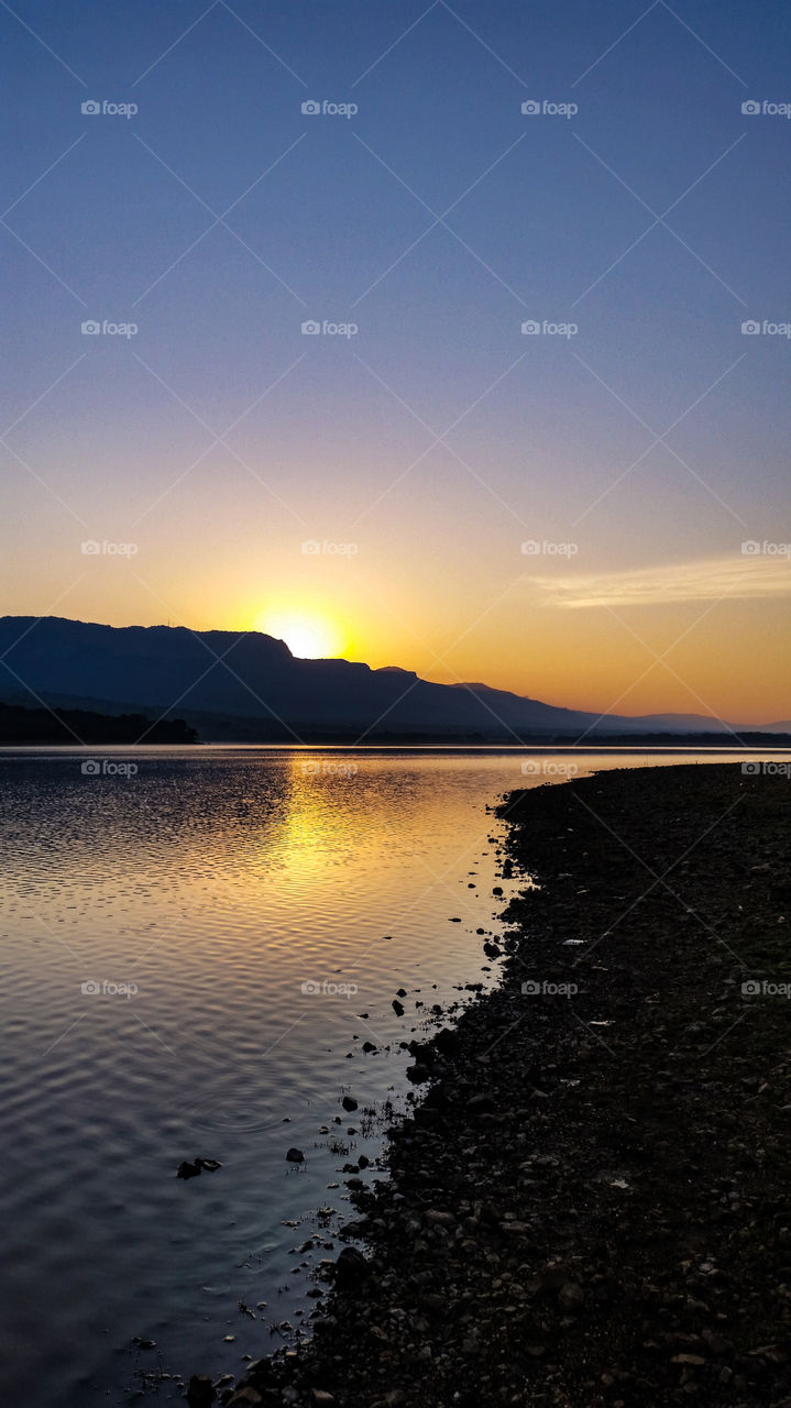 lakeside sunset behind a mountain