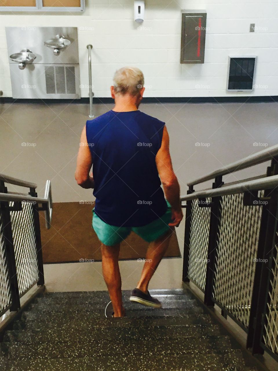Elderly healthy male at the gym walking down steps to exercise