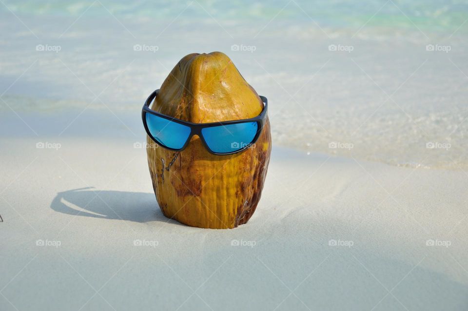 coconut with glasses on white beach