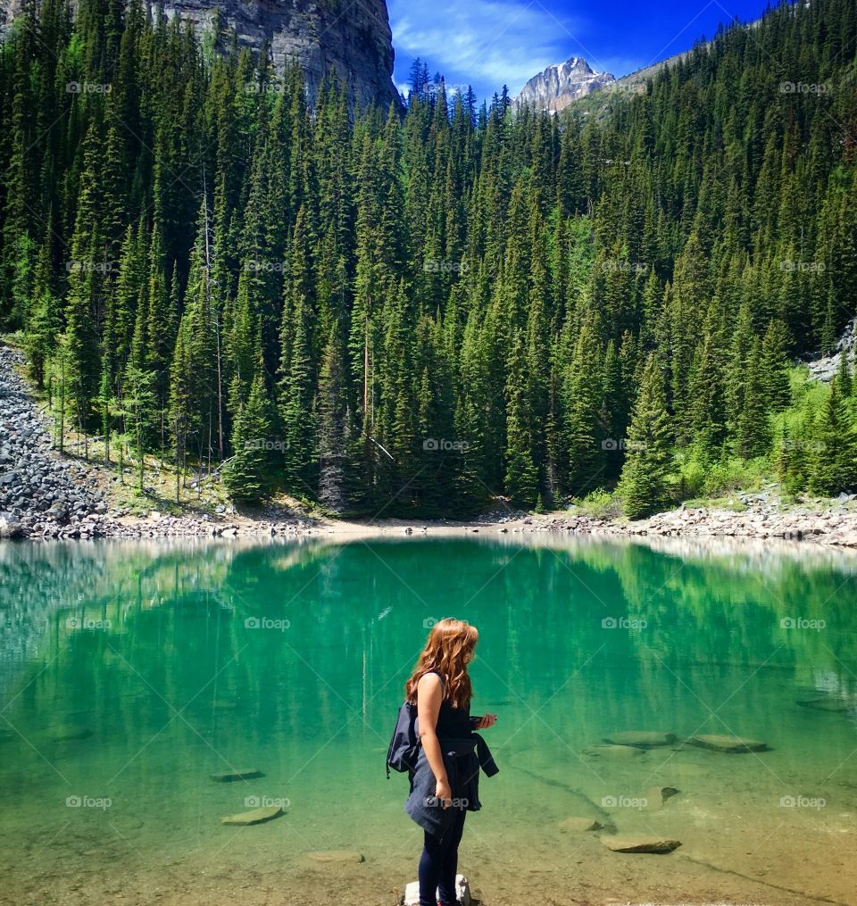 Woman standing against lake and trees