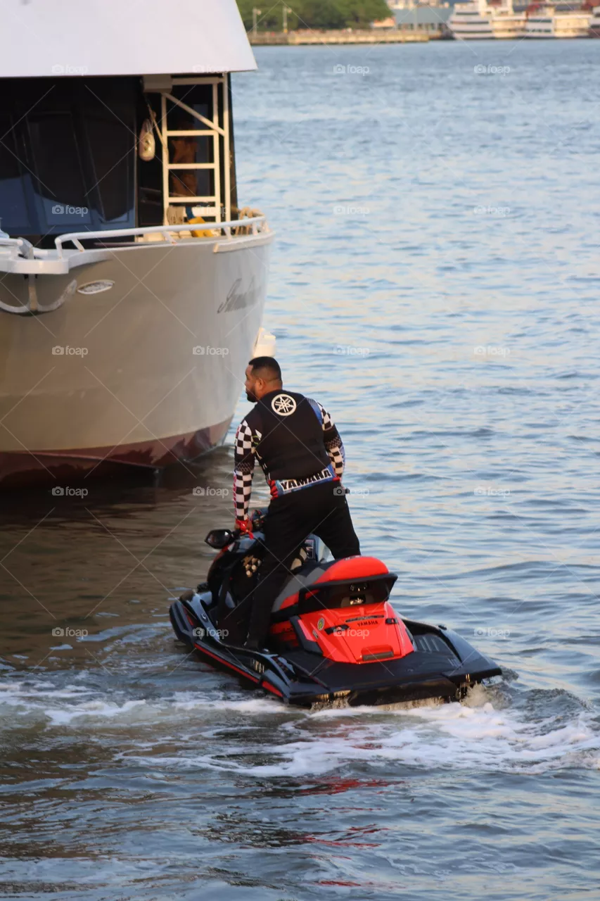 Man standing on jet ski near yacht on Hudson River 
