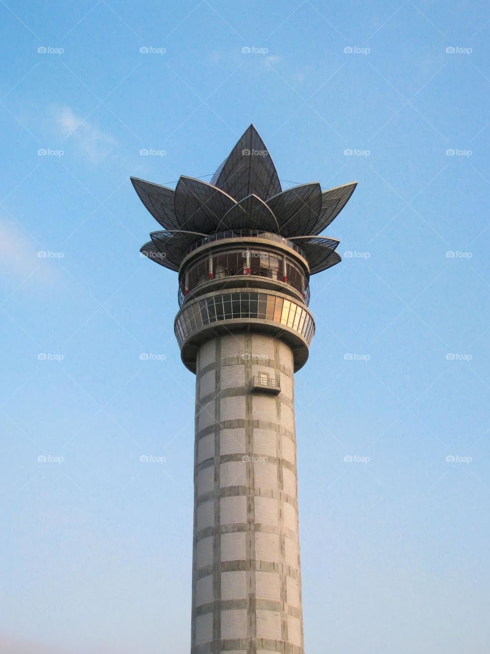 a tower with a lotus flower structure at its peak set against a clear sky