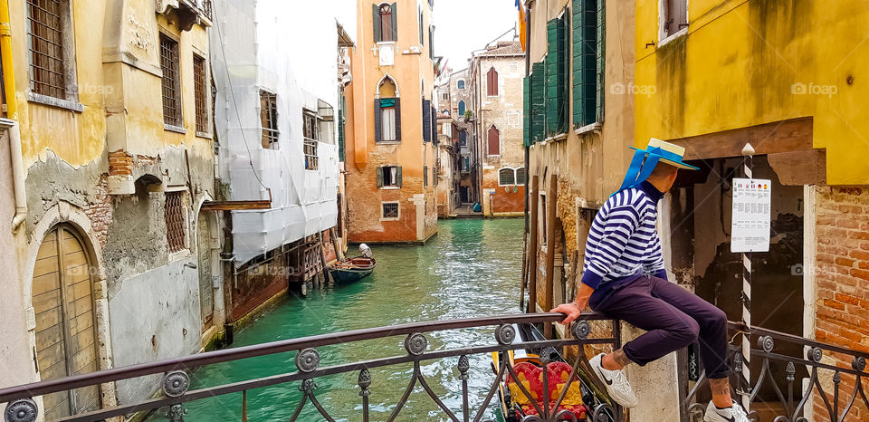 Typical canal scene in Venice with a gondolier patiently waiting for his next passenger
