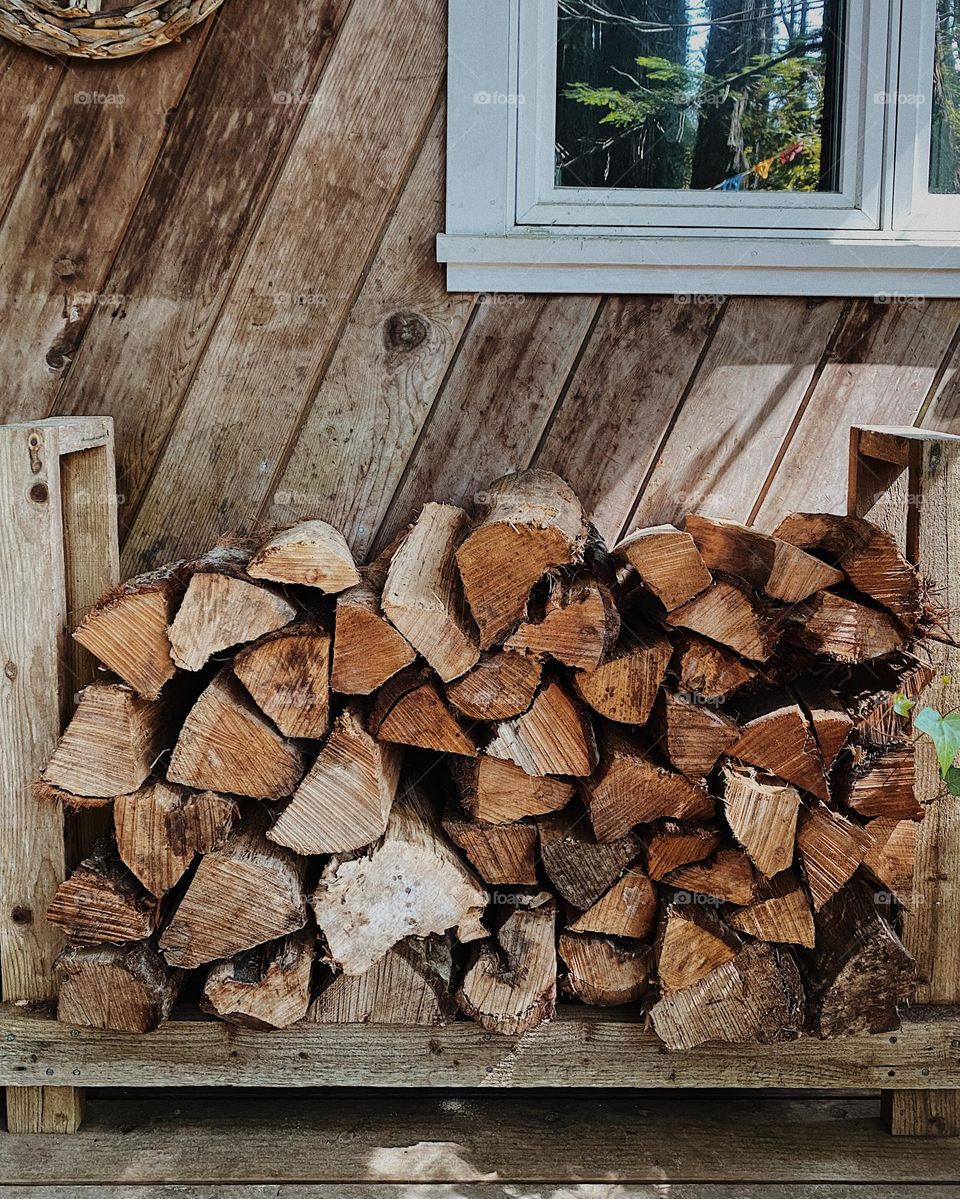 Logs stacked outside next to a cabin
