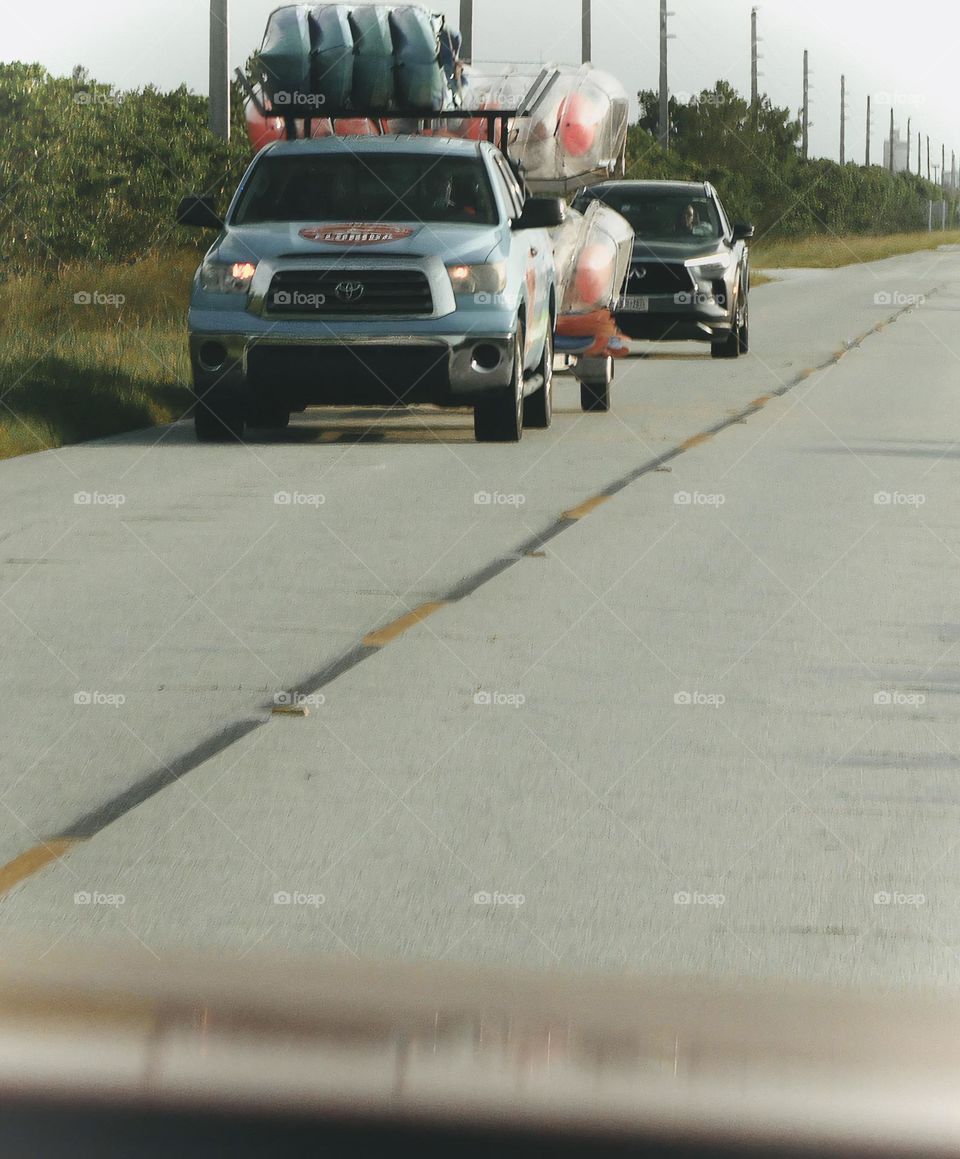 Commuting: Florida kayak team vehicles preparing for bioluminescent tourists for the night tour coming on the opposite direction on Merritt Island nature preserve road.