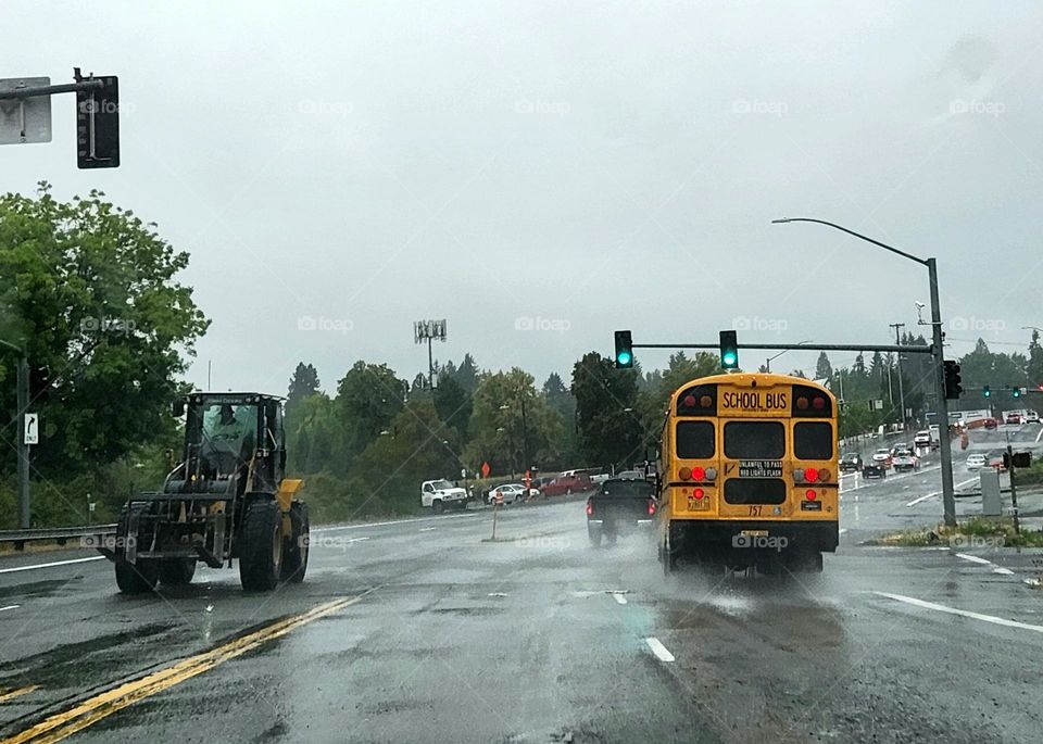 a yellow school bus driving through commuter traffic on a rainy Oregon morning gets the green light