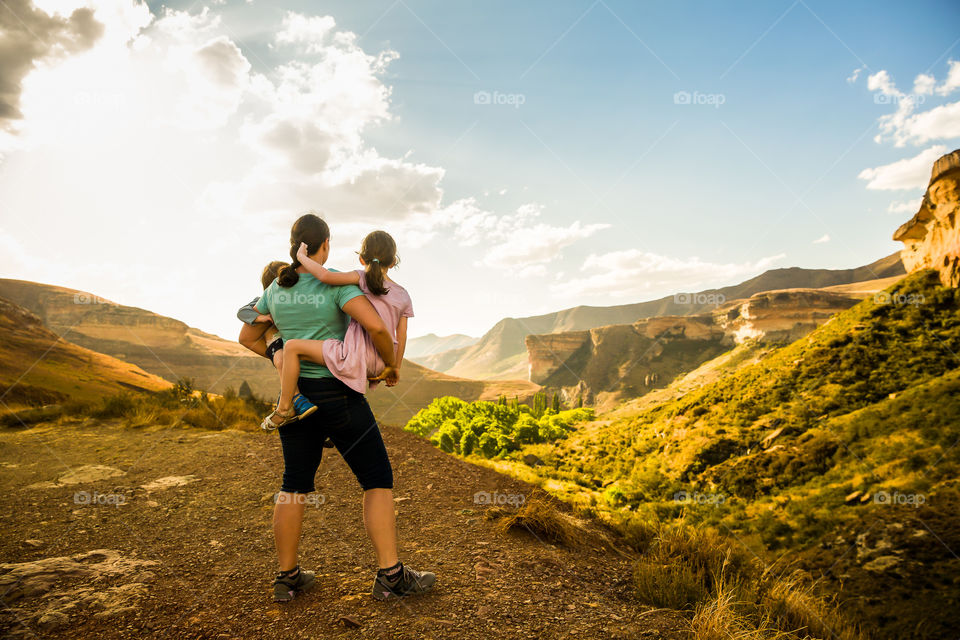 One of my favorite memories - time with my kids at Golden Gate national park in Africa. Image of woman holding her two children overlooking mountains and valleys at sunset