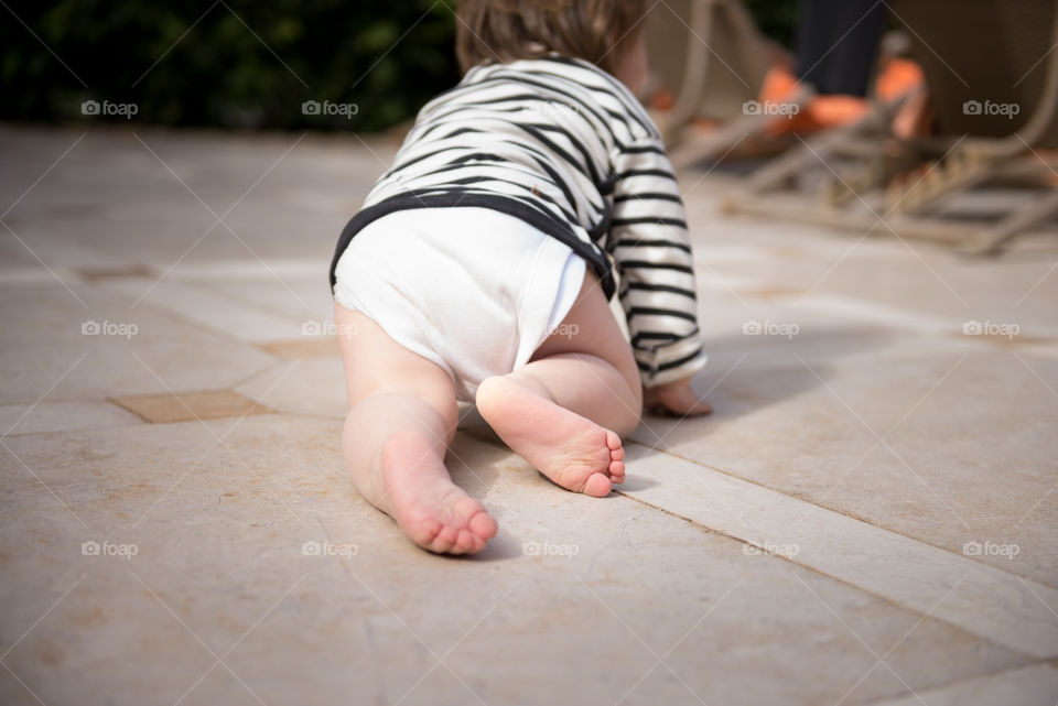 Rear view of baby crawling on floor