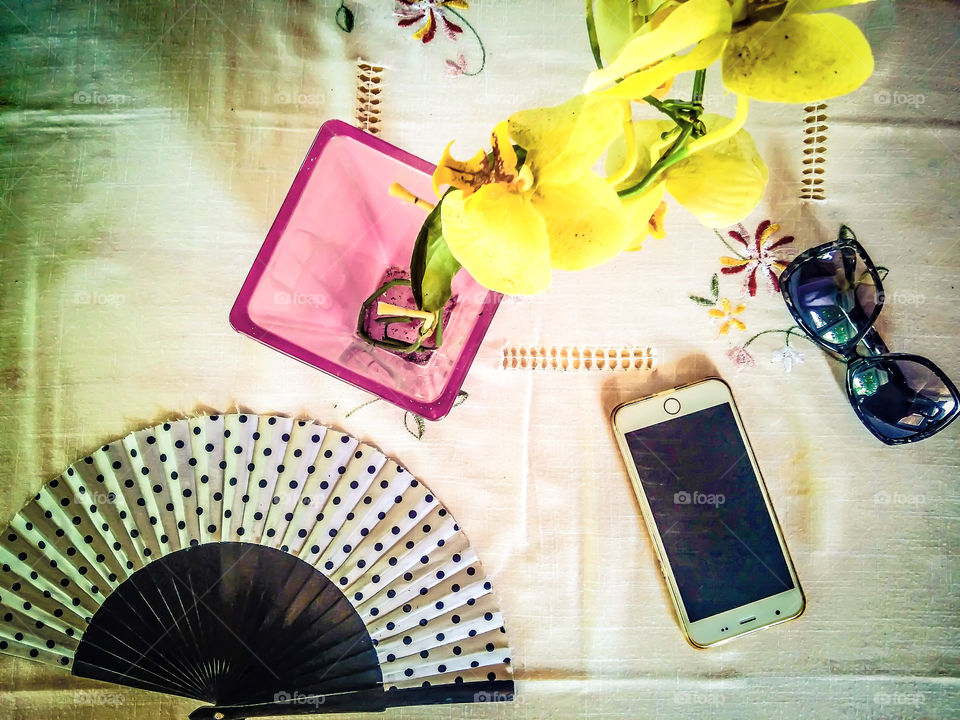 Cell phone, sunglass and hand fan on table
