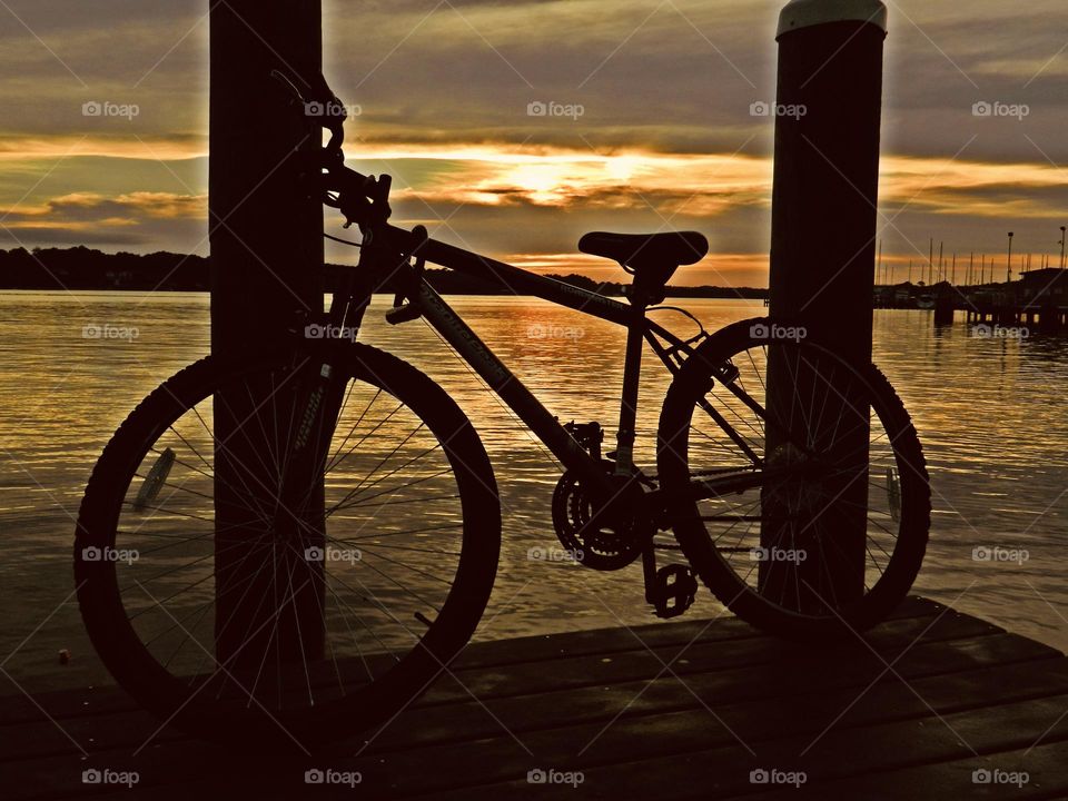 One Lonely Bicycle - After being ridden from sunrise to this spectacular sunset, the bicycle rests against two vertical posts from the marina dock