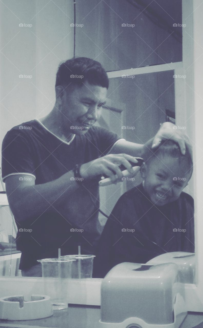 Man cutting hairs of a child