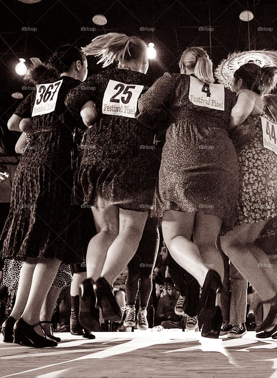 Sepia shot of the back of a group of women dancing and jumping at the Fisel dance competition in Rostrenen