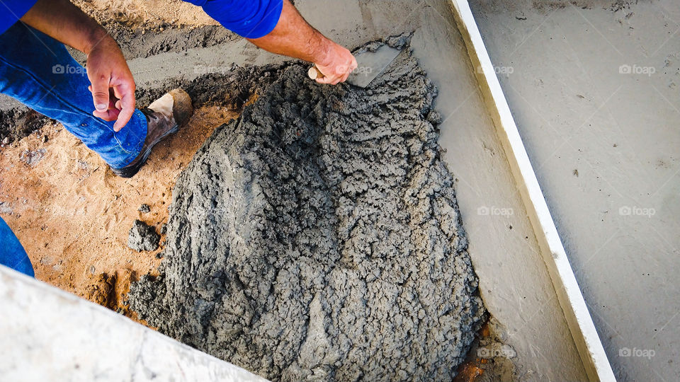 Trabalho. Pedreiro com colher fazendo calçada com concreto.
