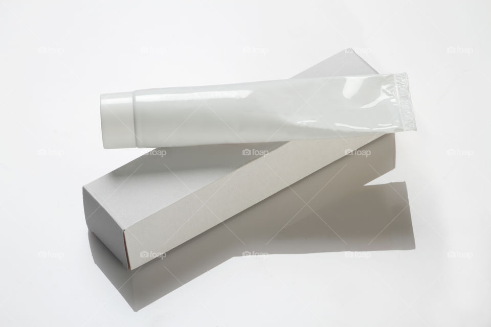 White toothpaste tube and box on reflective white background