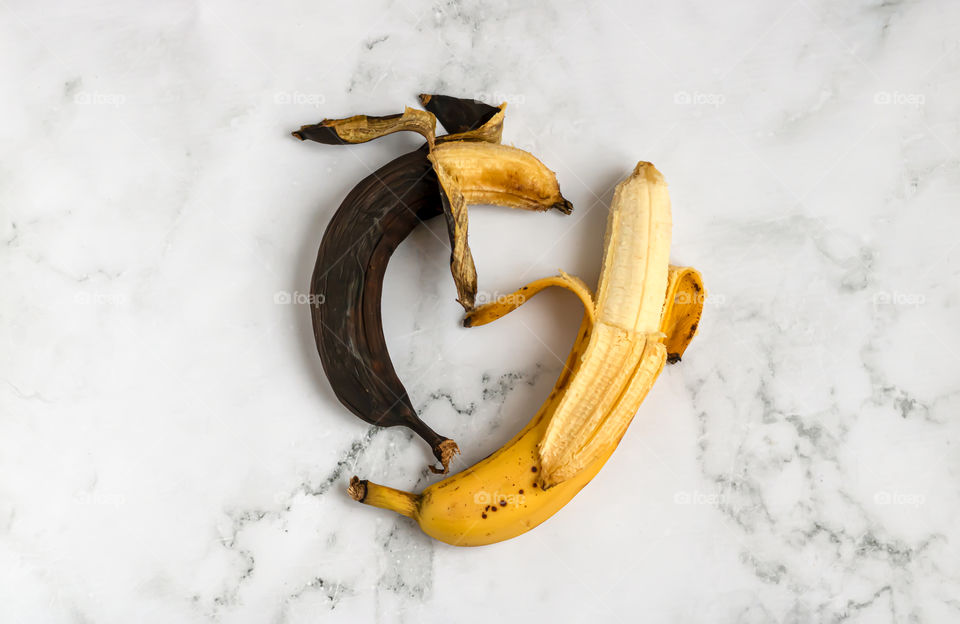 Top view to two overripe and ripe bananas on marble background.